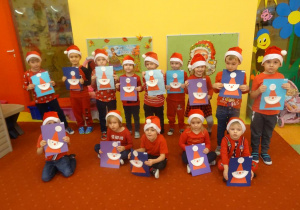 Grupa dzieci trzyma w ręku prace plastyczne- świętego Mikołaja.